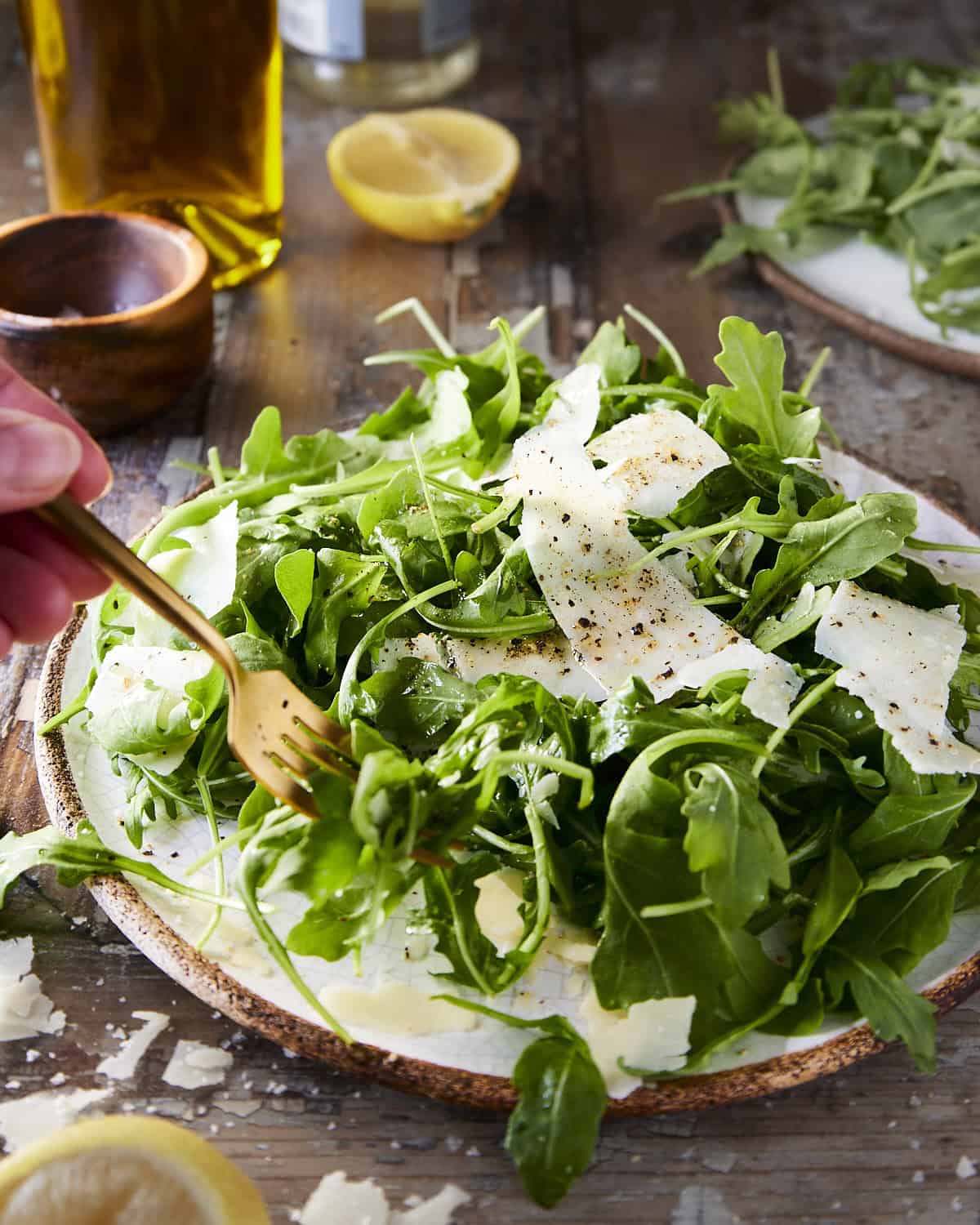 Eating a simple arugula salad with a fork on a wooden background.