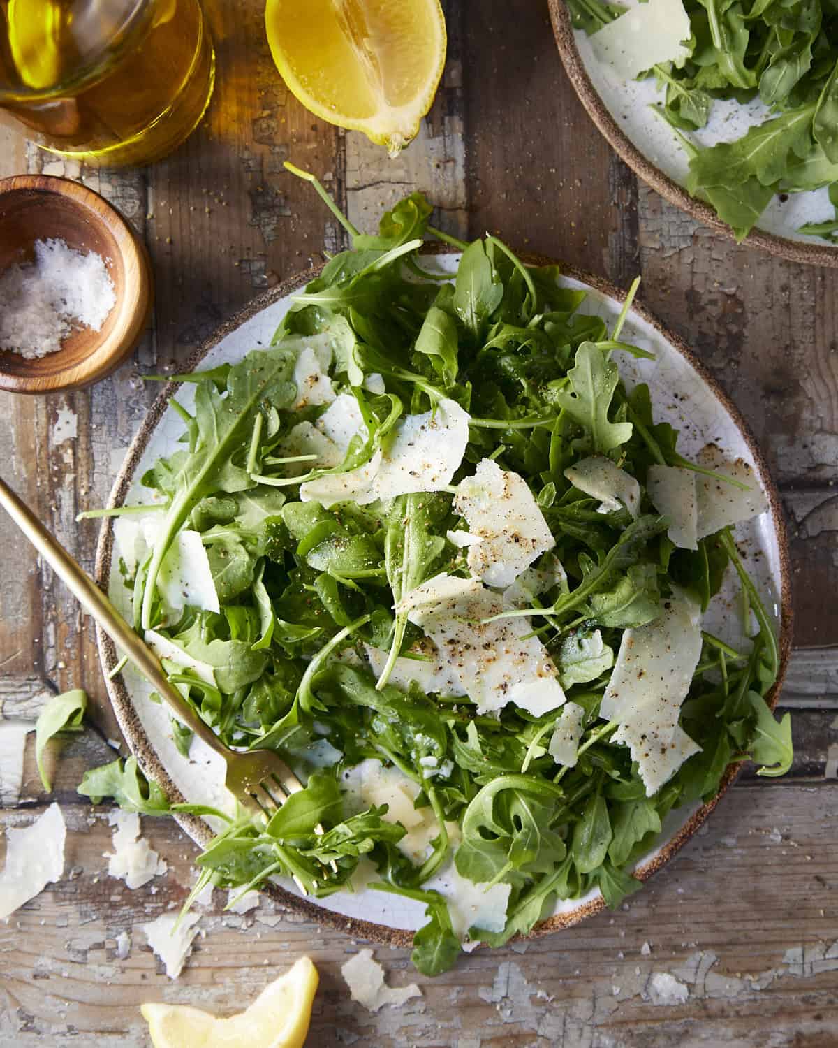 Overhead shot of a salad with arugula on a rustic plate with a rustic wooden background.