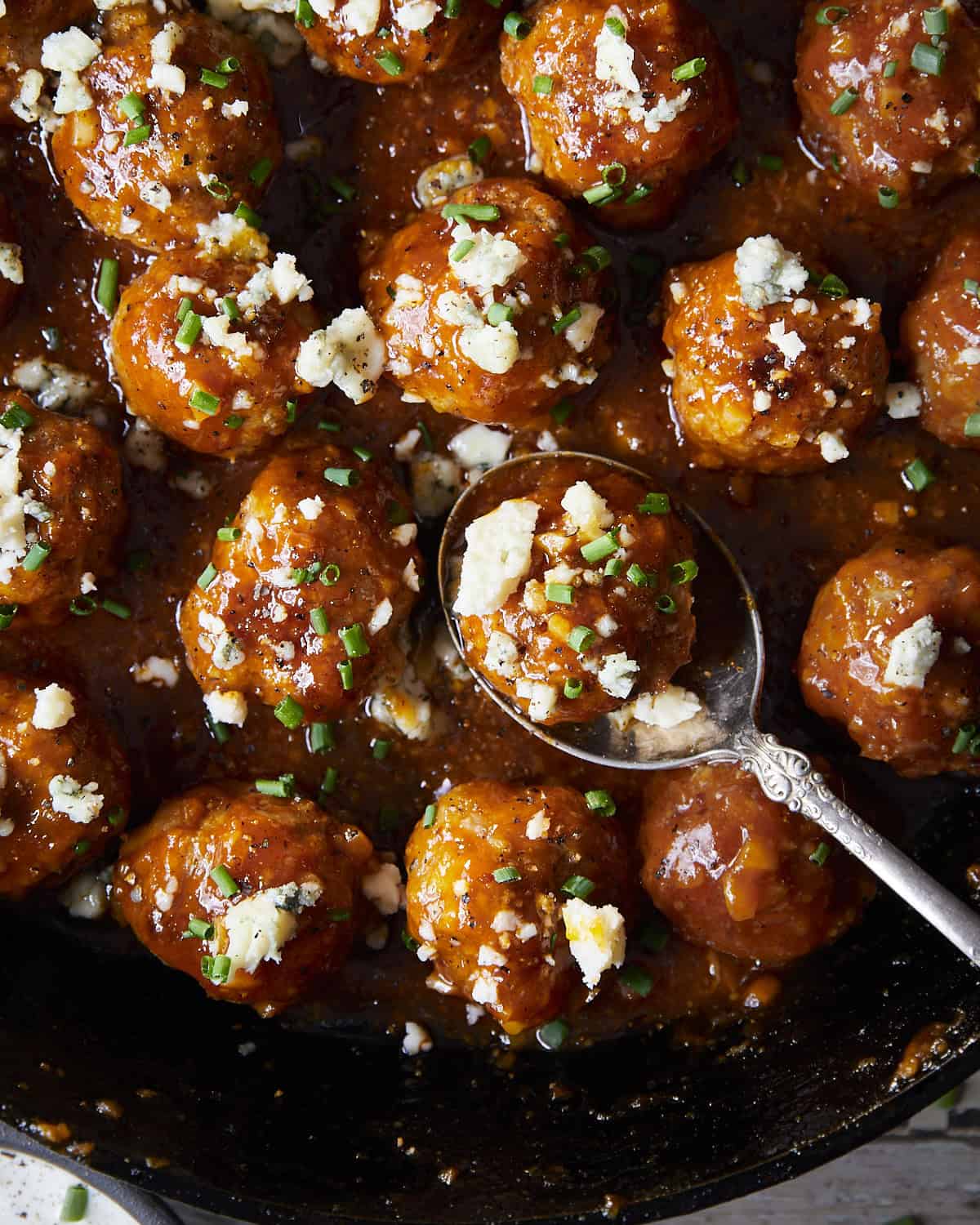 Overhead image of chicken meatballs in a skillet with a garlic buffalo honey sauce.