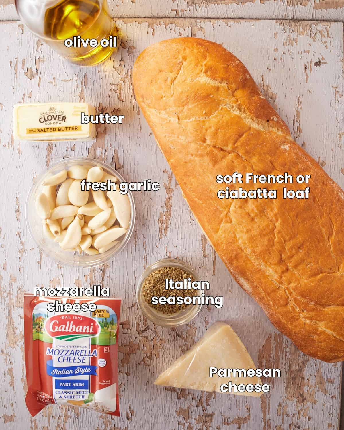 Ingredients needed for cheesy garlic bread are laid out on a wooden background. 