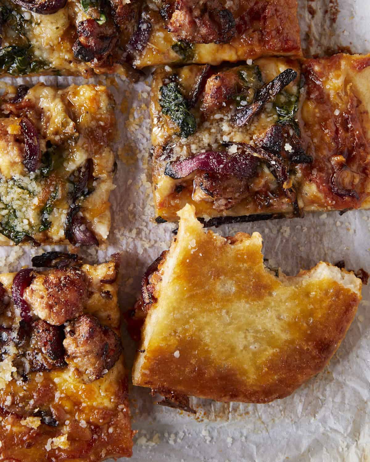 Pizza cut into squares with a bite taken out and flipped over to see how well bottom crust is cooked. 