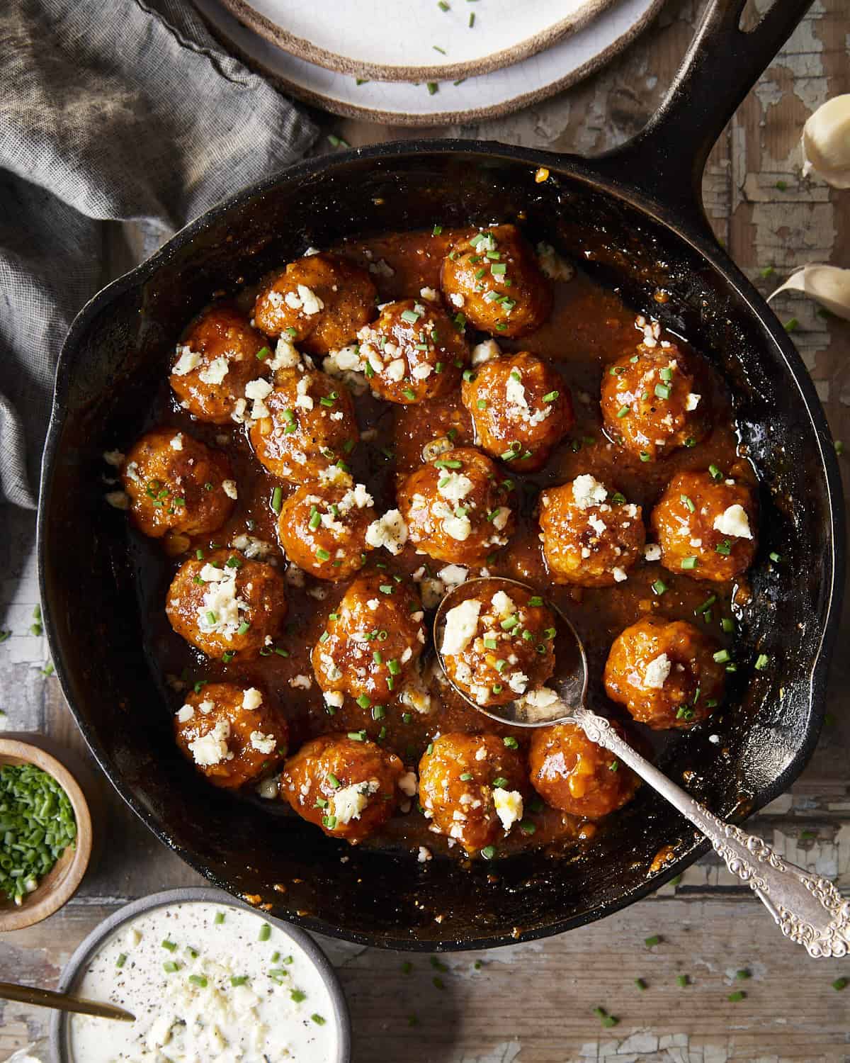 Chicken meatballs in a cast iron skillet with a garlic buffalo sauce and blue cheese crumbles.
