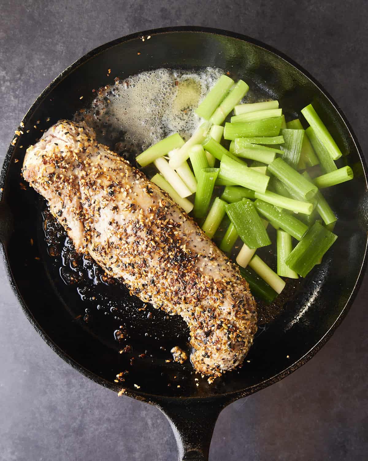Seared pork tenderloin with butter and scallions added to the pan.