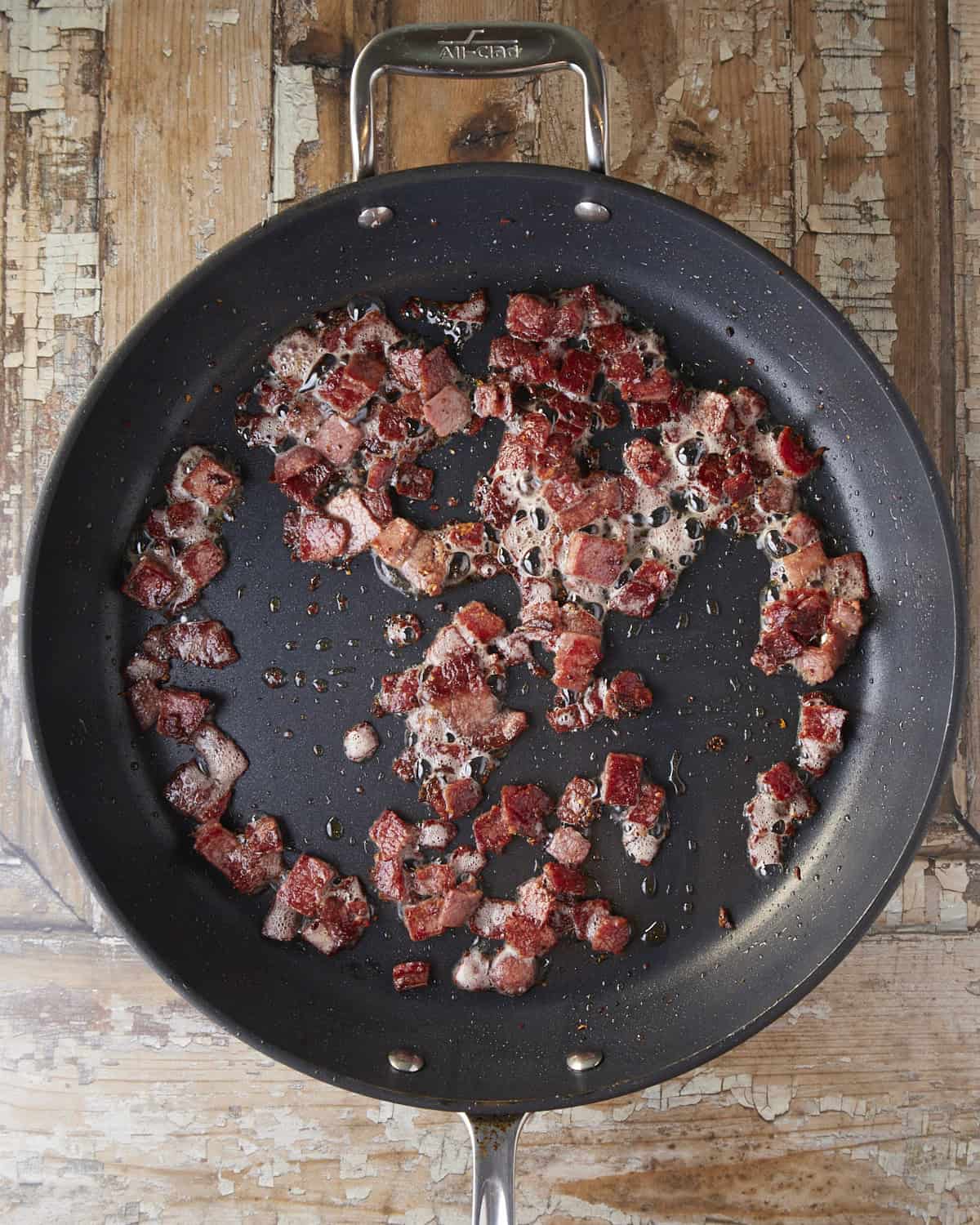 Pastrami is crisping up in a nonstick skillet.