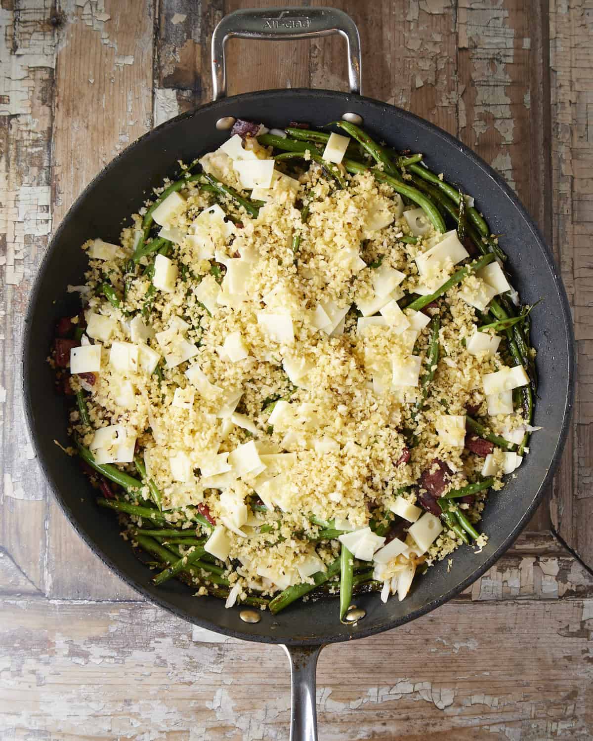 topping green beans with cheese and breadcrumbs.