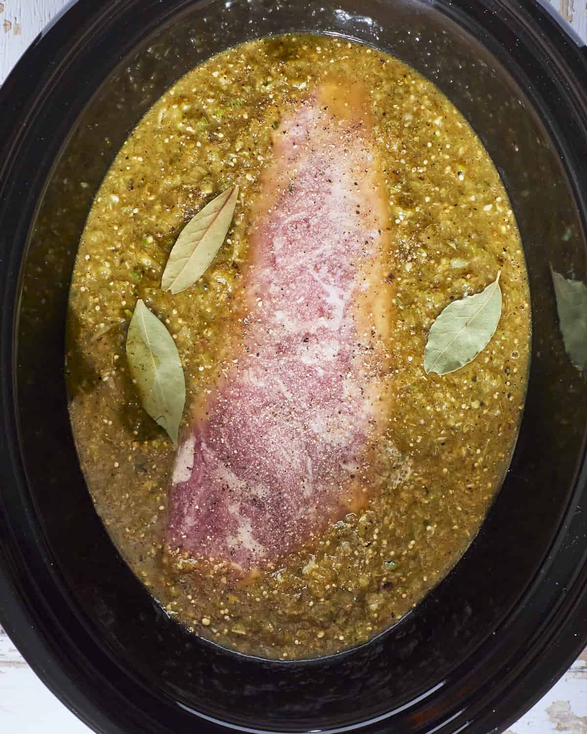 Chile verde with pork tenderloin in the slow cooker ready to be cooked.