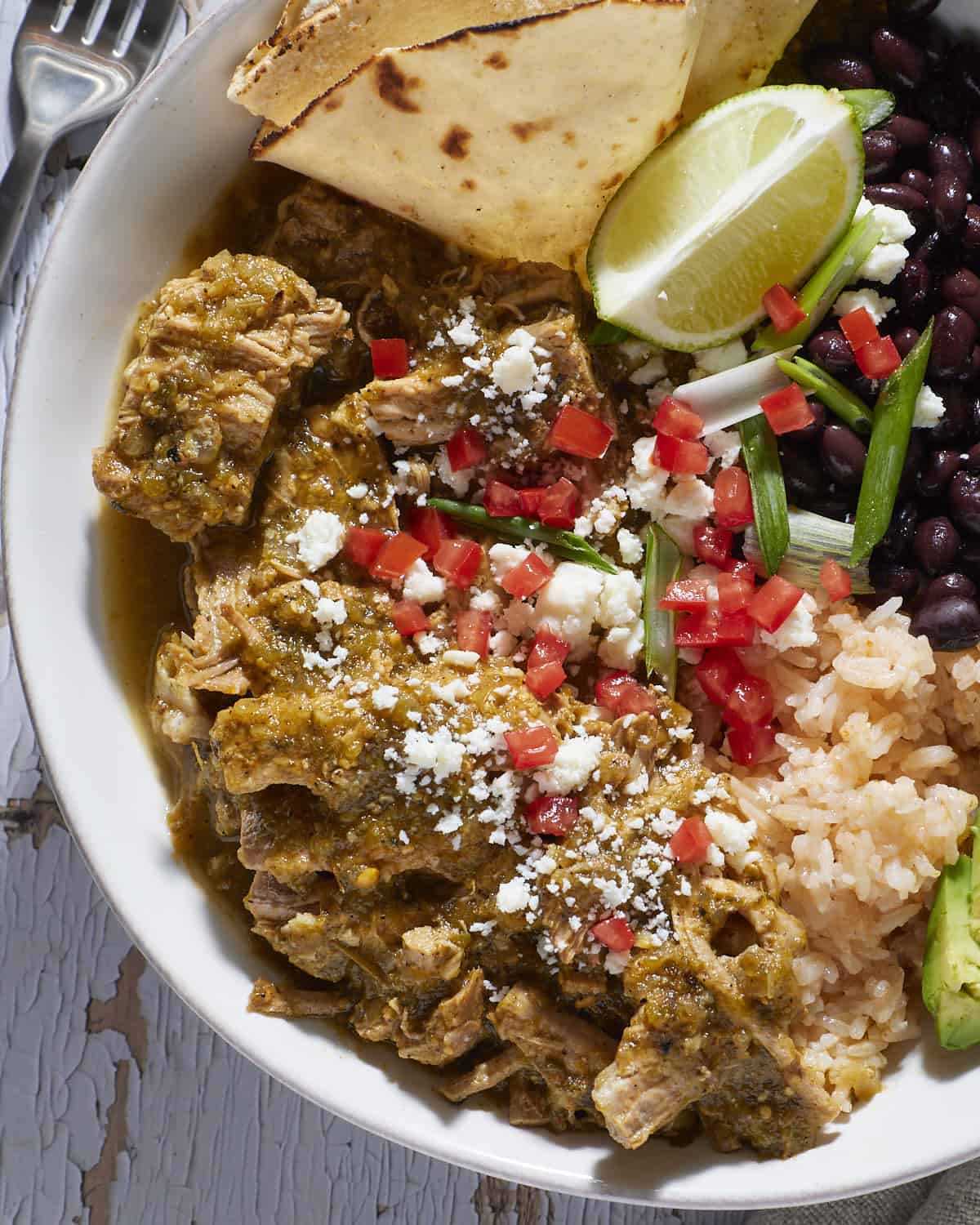 Up close of chile verde with pork tenderloin and garnishes. 