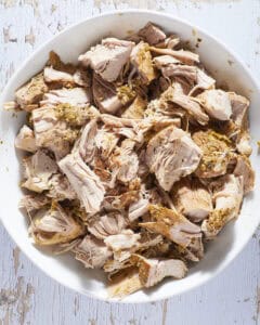 Tender pork tenderloin cut into large chunks in white bowl.